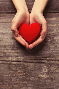 Photo. Cupped hands holding a red heart.